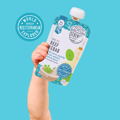 Hand holding a Serenity Kids beef kebab pouch against a blue background with 'World Mediterranean Explorer' branding.