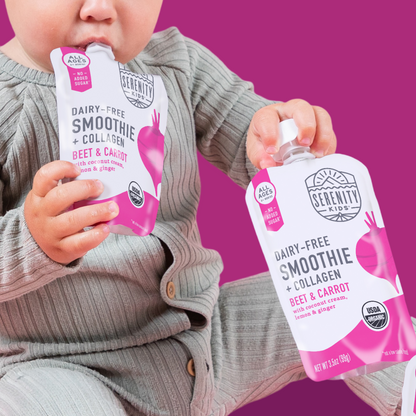 Child holding two packages of Serenity Kids dairy-free smoothie with beet and carrot flavor against a pink background