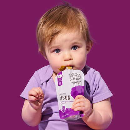 Baby holding a purple pouch with 'Serenity Kids' branding against a purple background