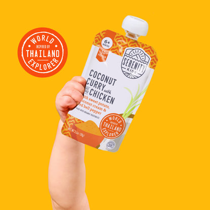 Hand holding a Serenity Kids coconut curry with chicken pouch against a yellow background