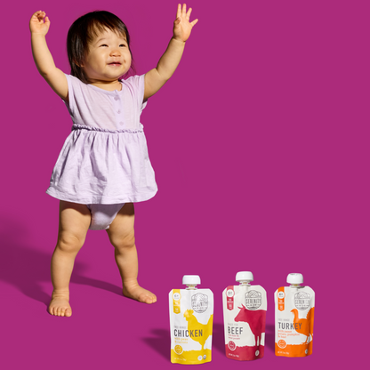 Child in a purple dress with baby food pouches on a pink background