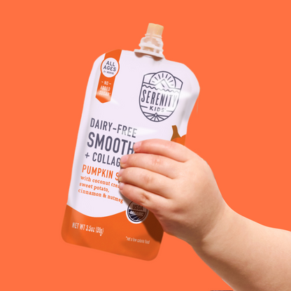 Hand holding a Serenity Kids pumpkin spice smoothie pouch against an orange background