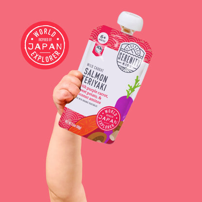 Hand holding a package of Salmon Teriyaki with vegetables against a pink background, featuring 'World Japan Explorer' branding.