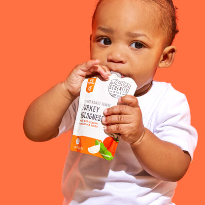Child holding a Serenity Baby food package against an orange background