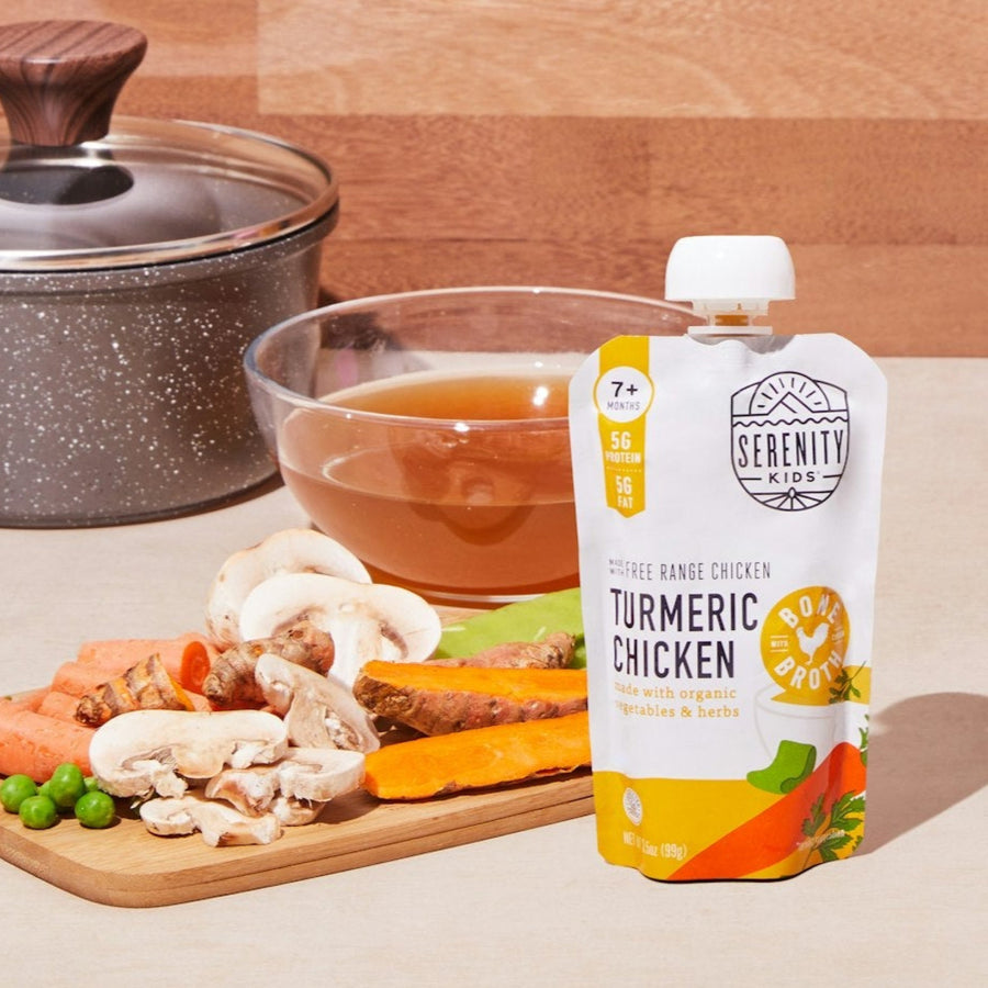 Serenity Kids turmeric chicken pouch on a table with food and ingredients in the background