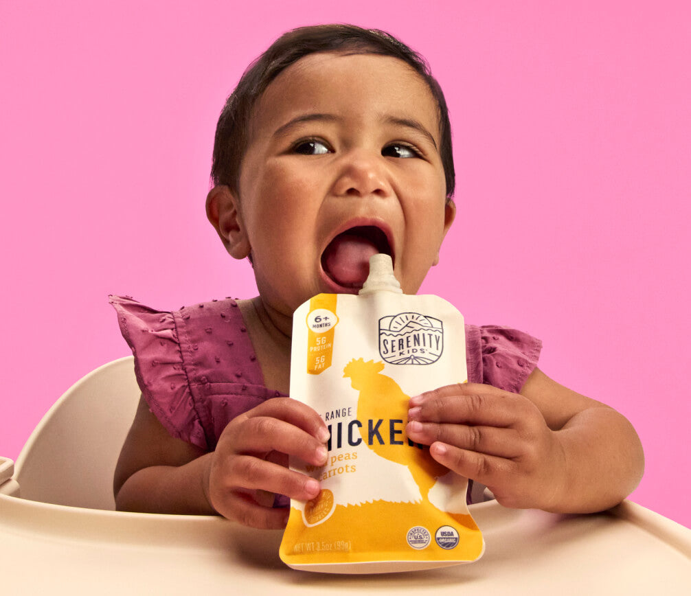 Baby happily eating from a Serenity Kids chicken pouch