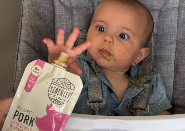 Baby holding a Serenity Kids pork pouch