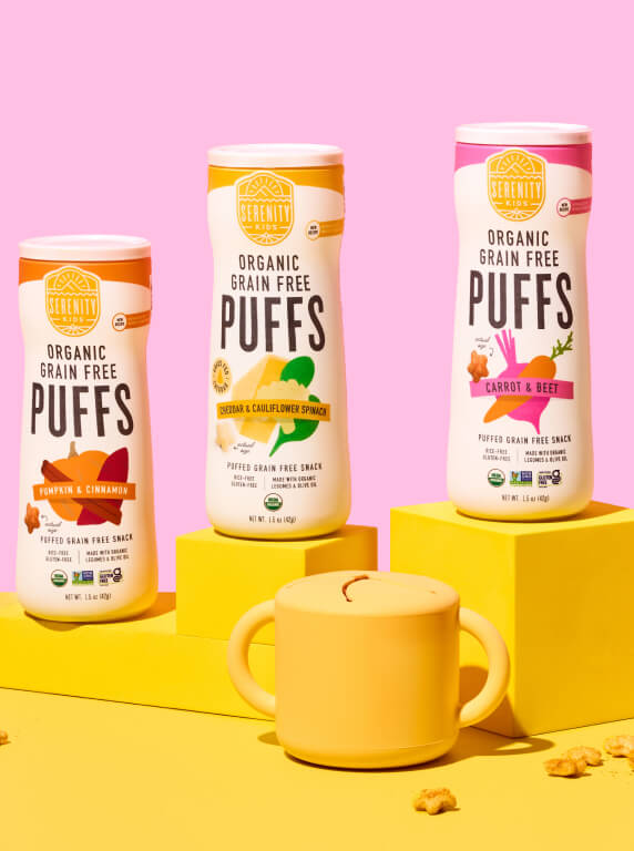 Three cans of Serenity Kids Organic Grain Free Puffs with a toddler cup