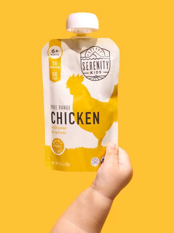 Baby hand holding a Serenity Kids Free Range Chicken pouch